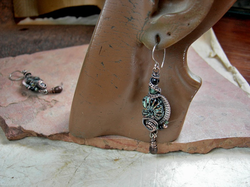Black glass nautilus bead earrings with oxidized copper wire wrap, glass tear drops & green and black gemstone beads.