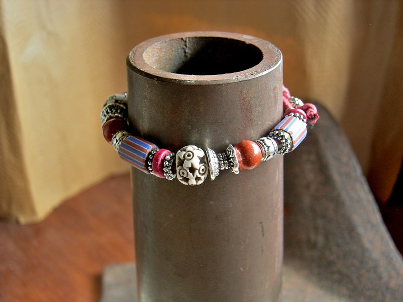 Sliding knot bracelet with red & blue striped Venetian glass, red jasper, carved bone & silver details. Red cotton cord.
