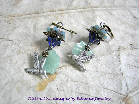 Silver hummingbird earrings with blue glass flowers, pale green glass leaf beads & antiqued brass and silver details. 