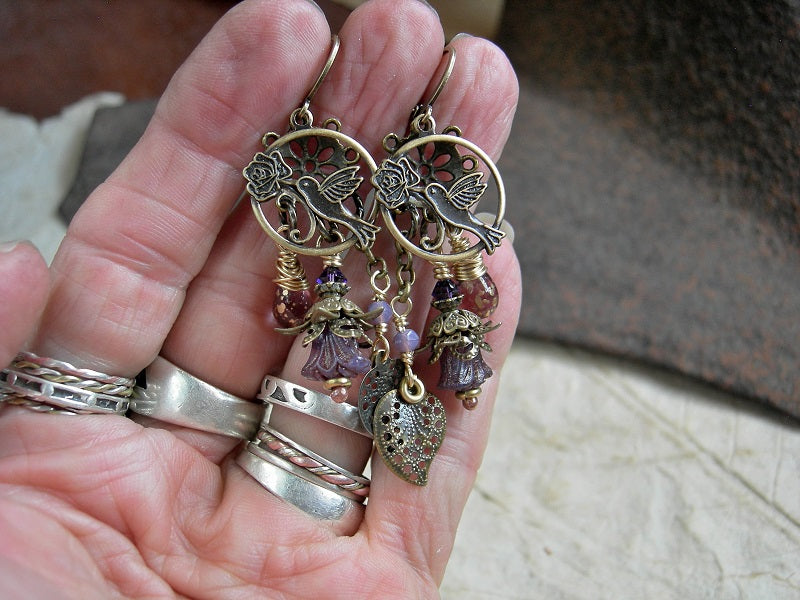 Boho nostalgic chandelier earrings with antiqued brass hummingbird & leaf charms, purple glass flowers & teardrops, Swarovski crystals.