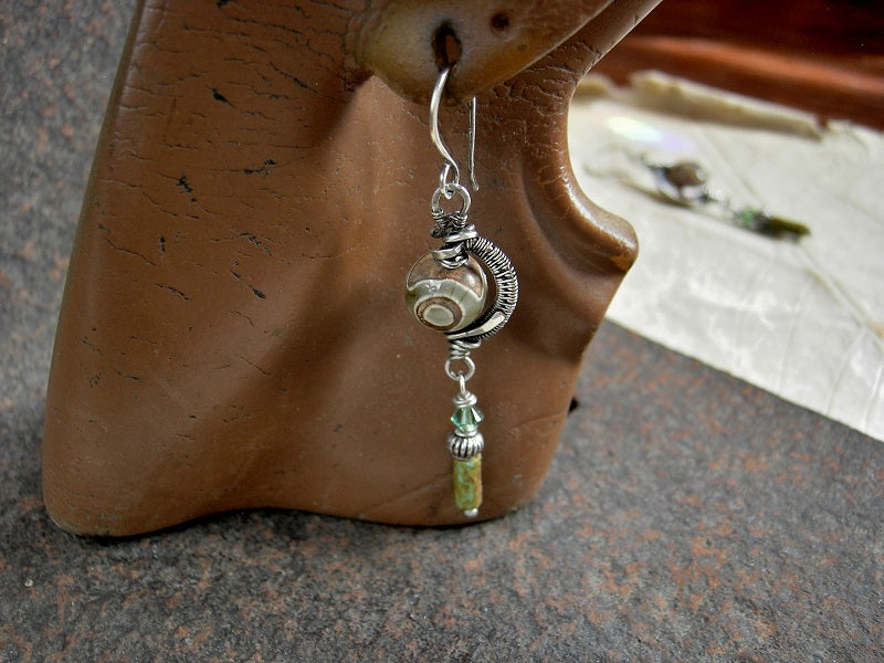 Etched agate rounds in sterling wire wrap curves with green/brown glass cylinders, silver beads & green Swarovski crystals.