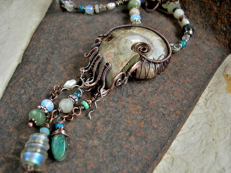 Treasure style boho luxe necklace with natural ammonite fossil in copper wire wrap & abstract mix of ocean color gemstone, opalite, glass & pearl beads.