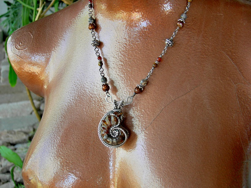 Golden amber colored, sterling wire wrapped ammonite necklace. Beaded sterling wrapped links with faceted amber, colored freshwater pearl, brown agate & tiger eye.