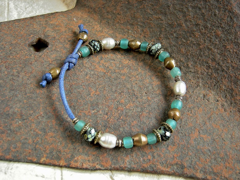 Adjustable slider bracelet with silvery white freshwater pearls, aqua Java glass, African brass & faceted black & Picasso finish Czech glass roller beads. 