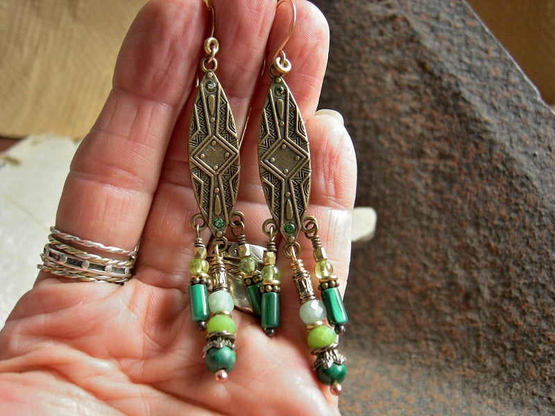 Dramatic chandelier earrings with elongated brass shield shapes, green gemstone and brass & golden beads & caps. 