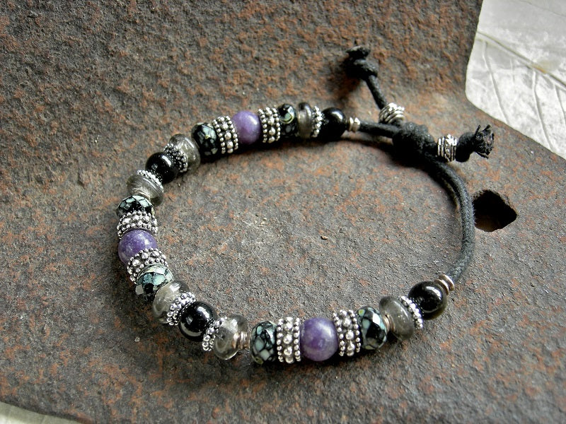 Adjustable sliding knot unisex bracelet with purple & black gemstone, black & grey glass and silver details. Black woven cotton cord.