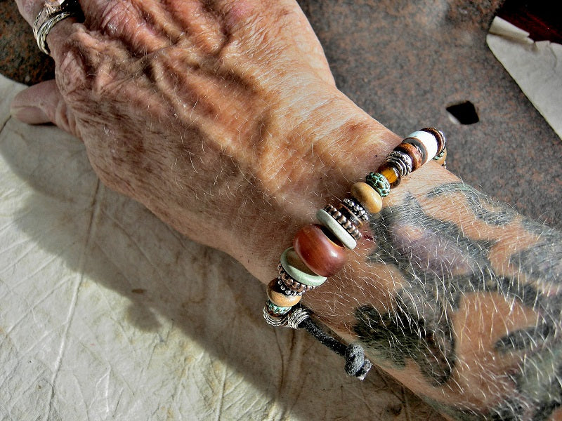 Adjustable slider bracelet with earthy southwestern colors in golden horn, ceramic, wood & glass. 