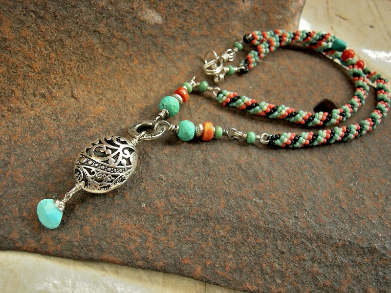 Woven seed bead necklace in turquoise, coral & black with turquoise & coral gemstone beads & silver filigree focal. 