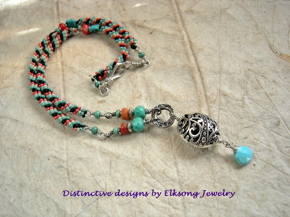 Woven seed bead necklace in turquoise, coral & black with turquoise & coral gemstone beads & silver filigree focal. 