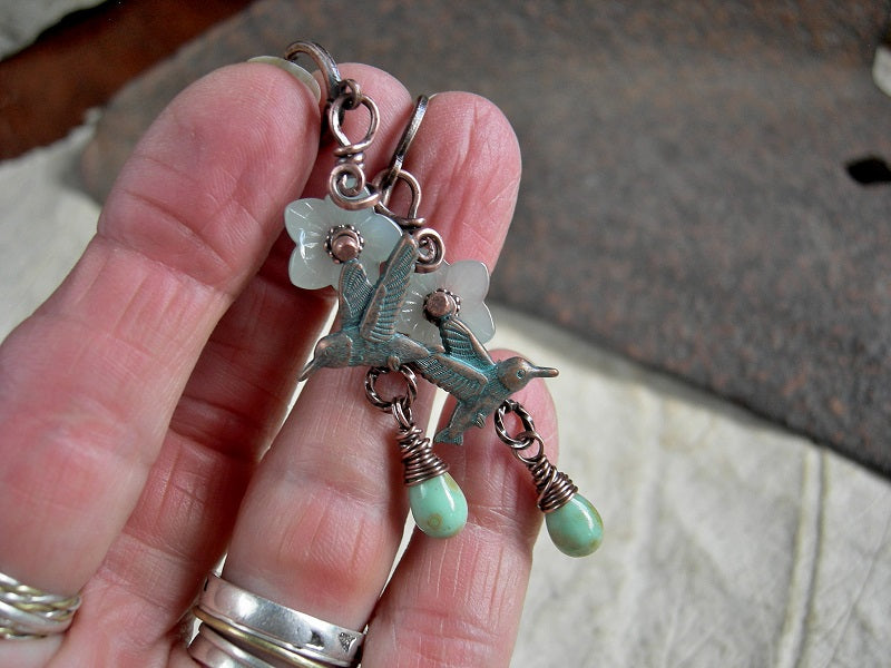 Glass & copper earrings with translucent pale green flowers, mint green tear drops & verdigris hummingbird charms. Lever back ear wires.