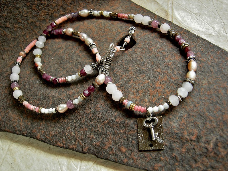 Wrap bracelet/necklace with antiqued bronze & silver lock & key focal, rose quartz, pink coral, mother-of-pearl, freshwater pearl, red tourmaline & thulite gemstone beads, mixed silver & antiqued brass beads. Adjustable sterling hook & eye clasp. 