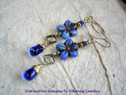 Blue flower-shaped earrings with gold accents, lapis gemstone & 14kt gf ear wires, branded 'Distinctive designs by Elksong Jewelry'.