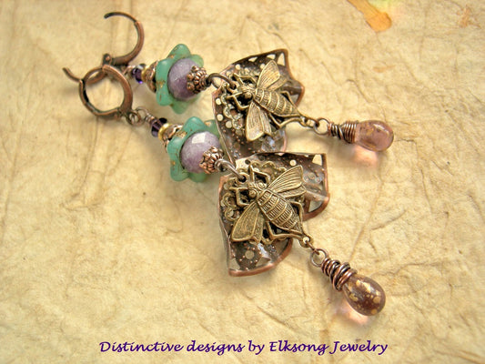 Ornate purple & green earrings with butterfly designs featuring Elksong Jewelry branding.