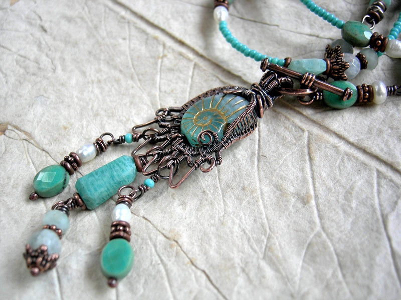 One of a kind necklace with glass nautilus & copper wire wrap focal, aqua gemstone & seed beads and front facing toggle clasp.