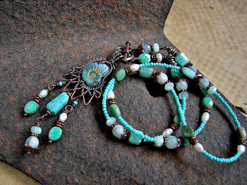 Boho luxe necklace with glass nautilus & copper wire wrap focal, aqua gemstone & seed beads and front facing toggle clasp.