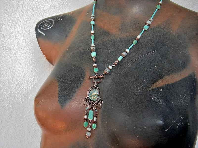 Bohemian necklace with glass nautilus & copper wire wrap focal, aqua gemstone & seed beads and front facing toggle clasp.